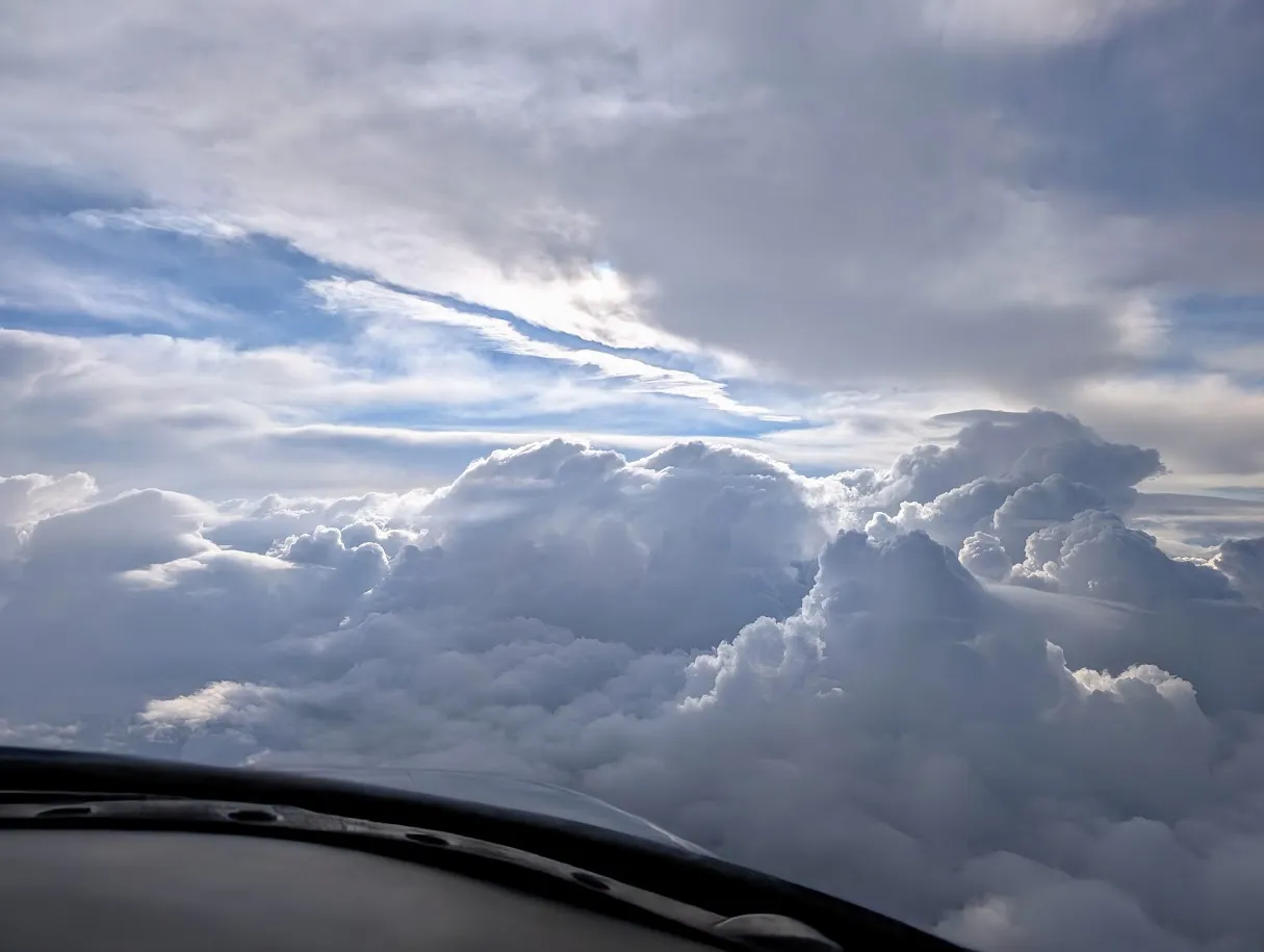 Plane heading towards towering clouds